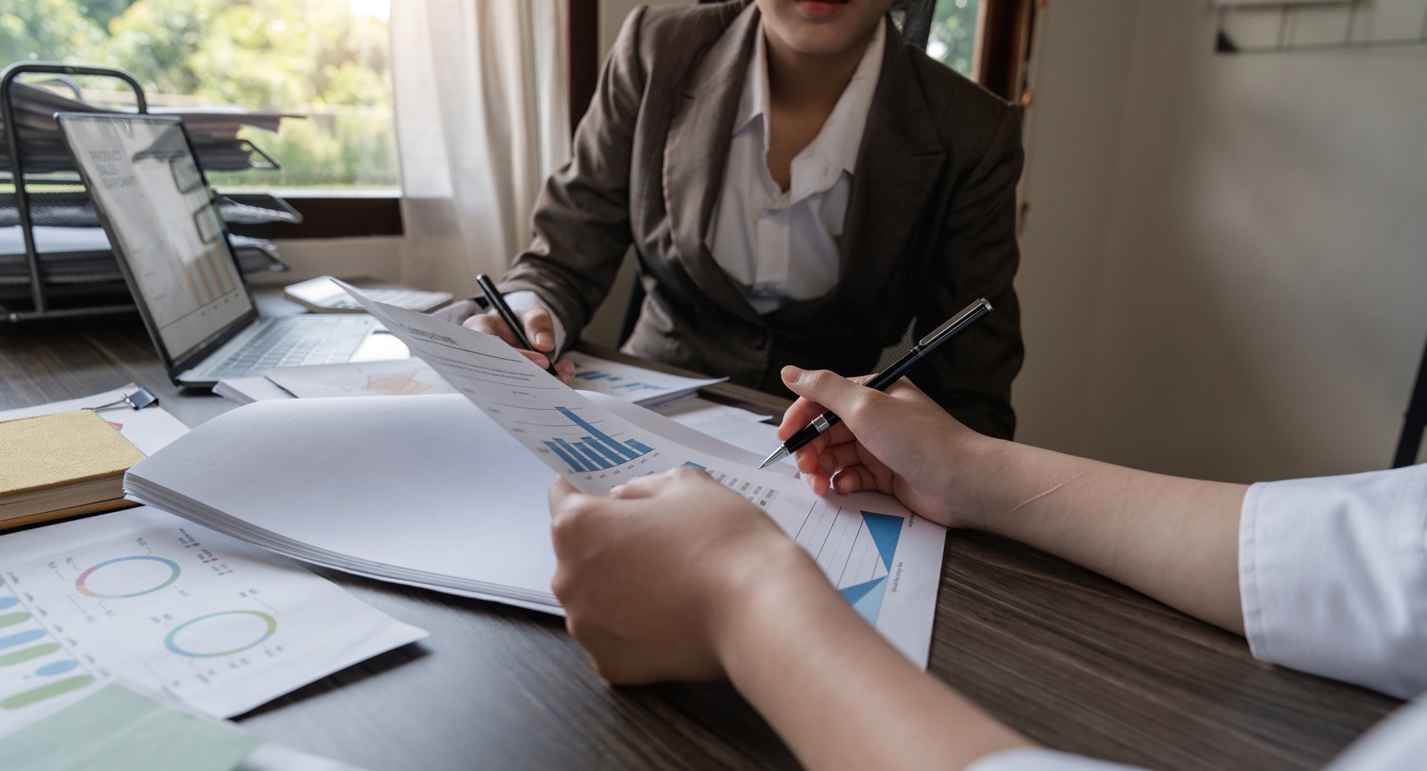 Two Asian business women Discussing Financial reports, analytical concepts, planning and financial